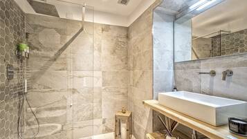 A modern bathroom with a rectangular sink, a glass shower enclosure, and a large mirror.