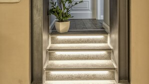 A staircase with a potted plant, a white door, and a light fixture. - Magenta Collection Sant'Anna (Rome)