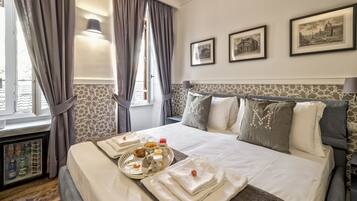 A neatly made bed with pillows, a tray of breakfast items, and a window with curtains.