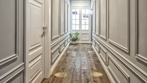 A hallway with white paneled walls, wooden flooring, and a door at the end. - Magenta Collection Sant'Anna (Rome)
