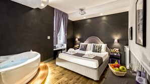 A modern hotel room with a large bed, a bathtub, a small desk, and a fruit basket. - Magenta Collection Sant'Anna (Rome)
