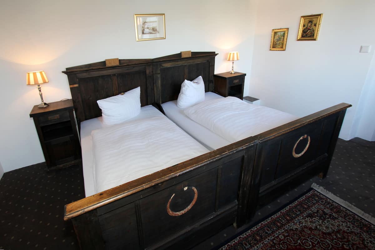 A double bed with wooden headboard and drawers, two bedside tables with lamps, and a patterned rug on the floor.