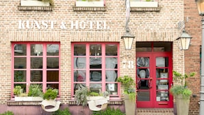 A hotel with a brick facade, large windows with pink frames, and a red door. - Hotel an de Marspoort (Xanten)
