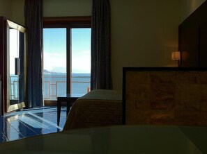 A hotel room with a large window, a bed, a chair, and a view of the sea. - Hotel La Lucertola (Vietri sul Mare)