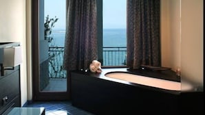 Un baño moderno con un ventanal grande, una bañera y vistas al mar.