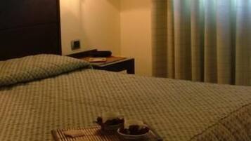 Une chambre d’hôtel avec un lit, une table de chevet, une lampe et une fenêtre avec des rideaux.