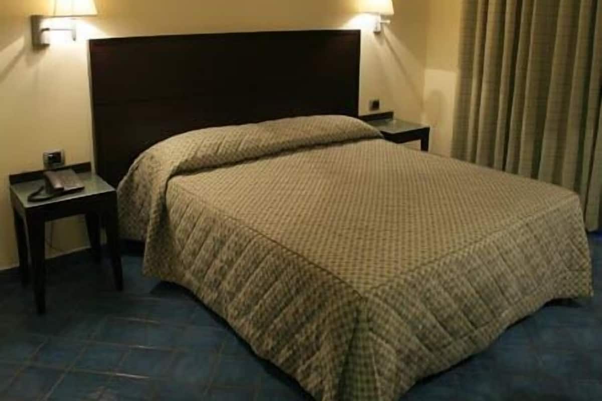 A hotel room with a large bed, two bedside tables, and a headboard.