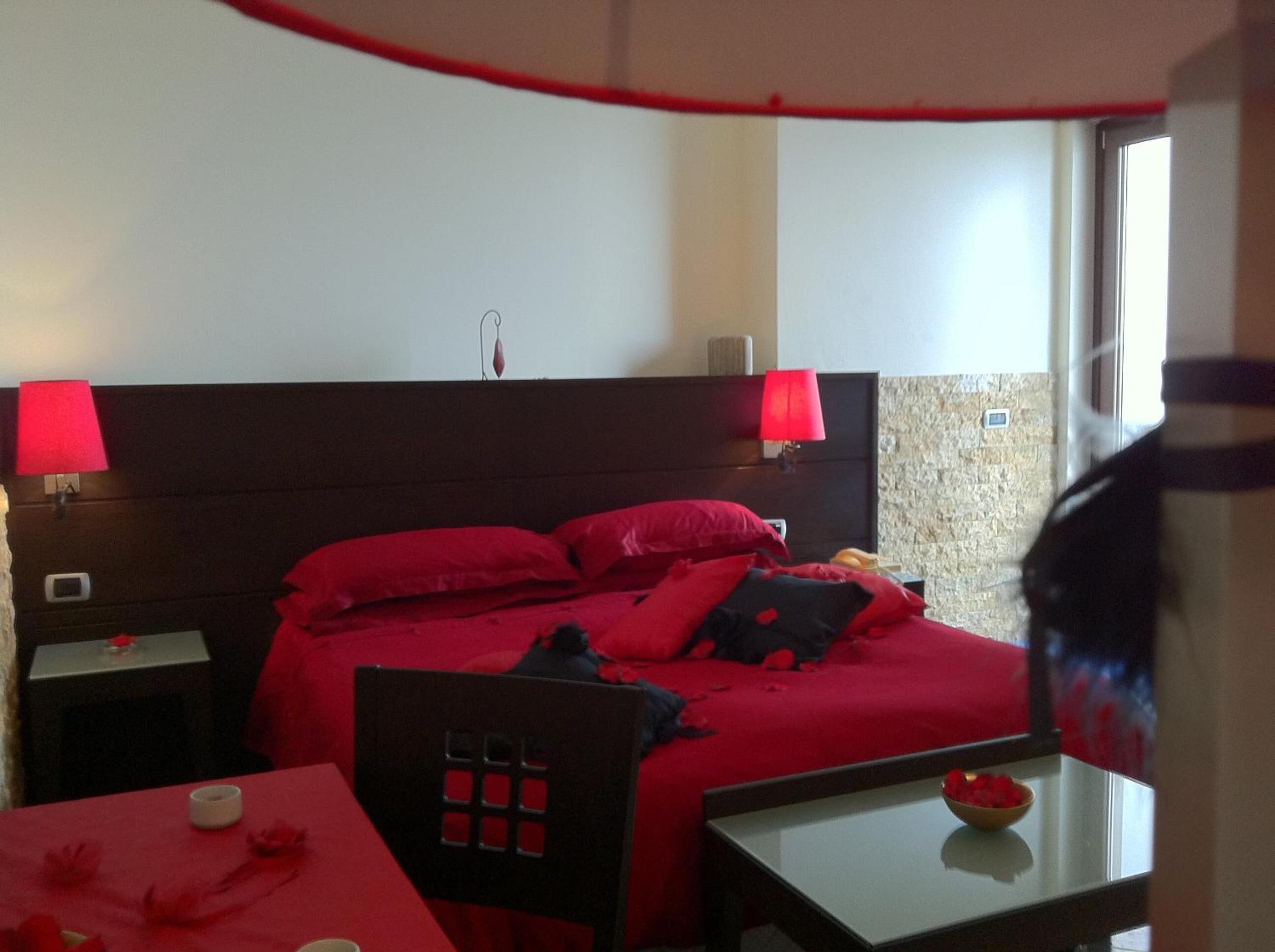 A hotel room with a large bed, two bedside lamps, a small table with a bowl, and a chair.
