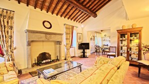 A cozy living room with a fireplace, comfortable seating, and a television. - Campoli (San Casciano in Val di Pesa)
