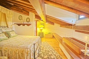 A bedroom with a wooden ceiling, a bed with floral bedding, a bedside table, and a nightstand.