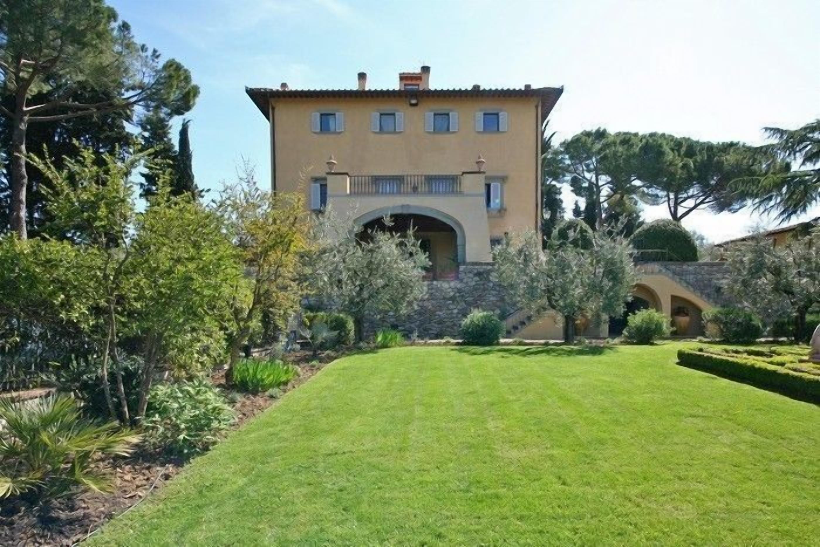 A two-story building with a stone facade, a central archway, and a well-maintained lawn in front.