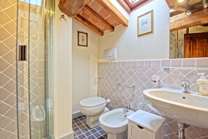 A bathroom with a shower, toilet, bidet, and sink.