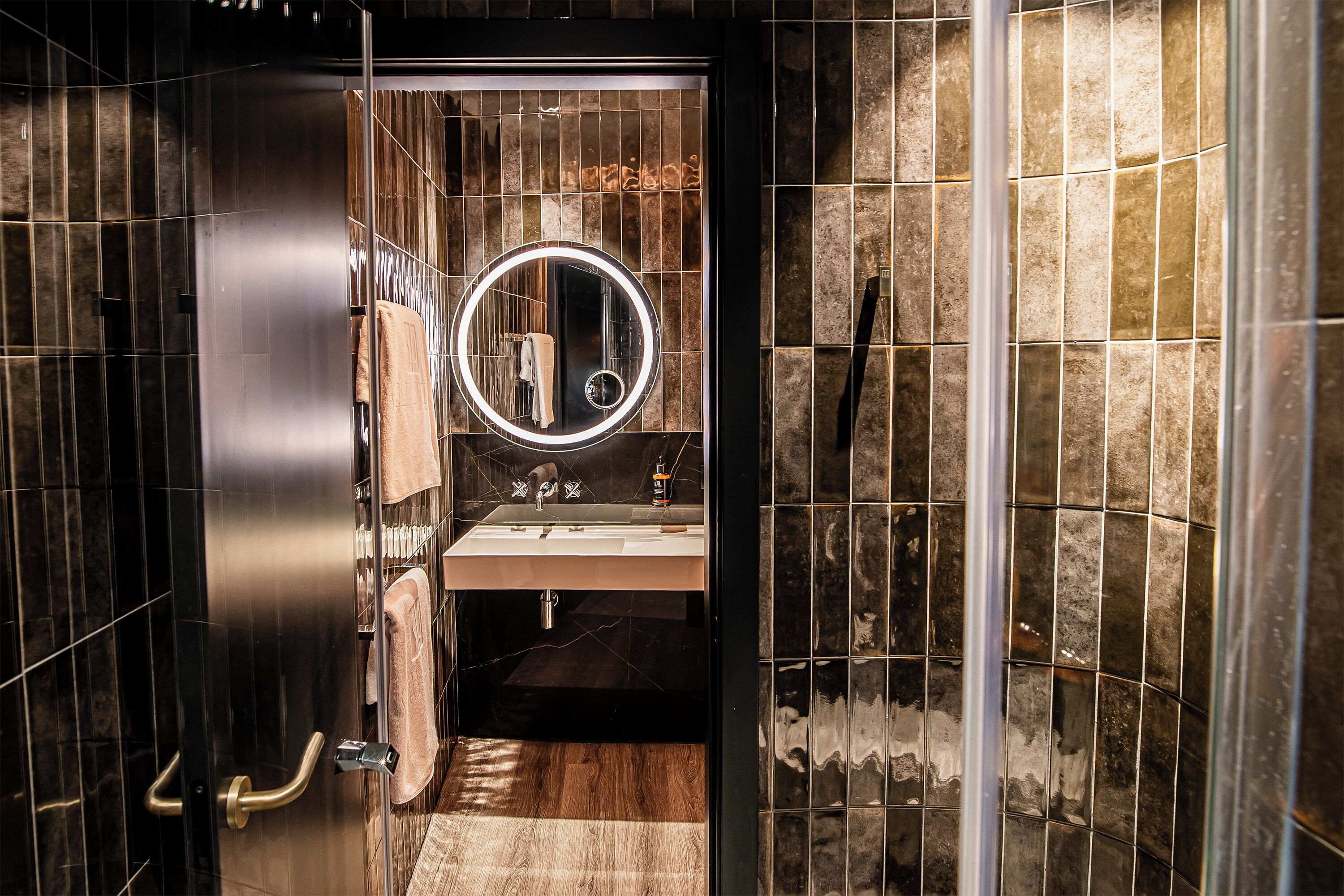 A modern bathroom with a vanity, mirror, and towel rack.