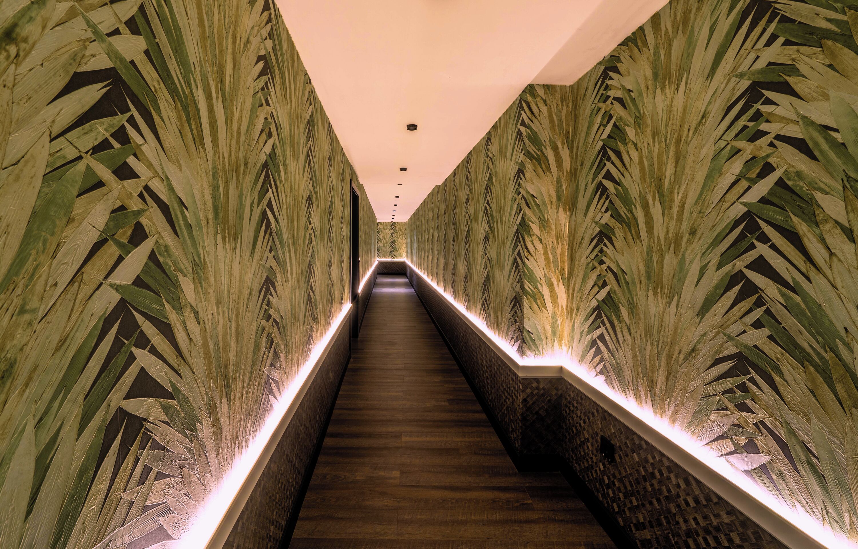 Una escalera estrecha, bien iluminada, con paredes decoradas y barandales iluminados.