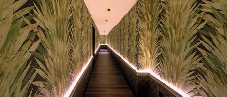 Una escalera estrecha, bien iluminada, con paredes decoradas y barandales iluminados.