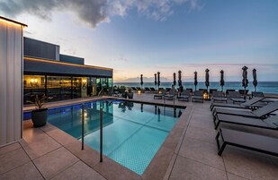 Una piscina al aire libre, sombrillas, sillones reclinables de piscina