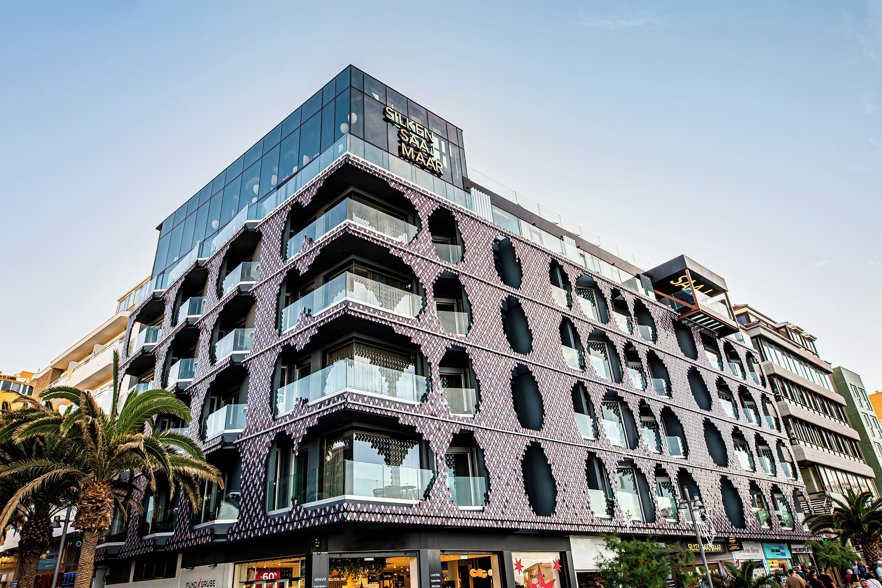 A modern building with a glass facade and patterned exterior.