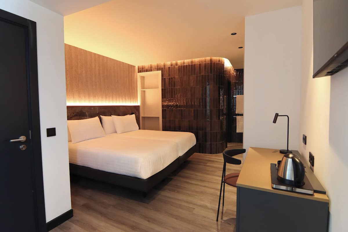 Una habitación de hotel moderna con cama, escritorio con tetera y armario.