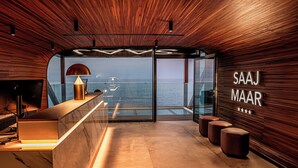 Un intérieur moderne avec un plafond en bois, un comptoir d’accueil et un mur de verre donnant sur la mer.