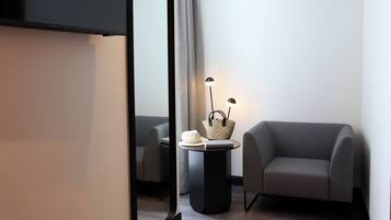 A modern room with a sofa, a small table with a lamp, and a mirror.
