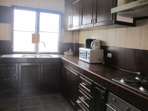 A kitchen with dark wooden cabinets, a built-in microwave, and a stove.