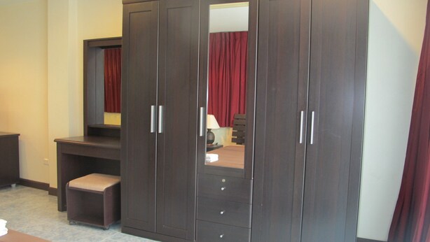 A bedroom with a large wardrobe, a desk, and a bed. - Rouge Service Apartments (Pattaya)