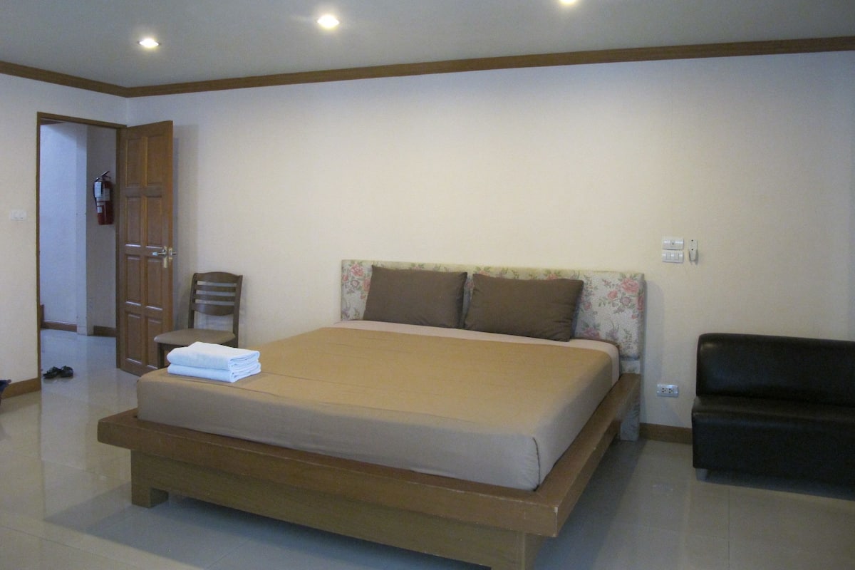 Um quarto com uma cama, uma cadeira, um sofá e uma porta.