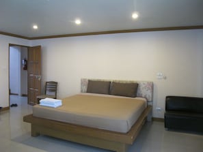 A bedroom with a bed, a chair, a sofa, and a door.
