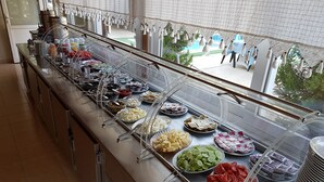 Buffet-pöytä, jossa on tarjolla monenlaista ruokaa ja ruokailuvälineitä.