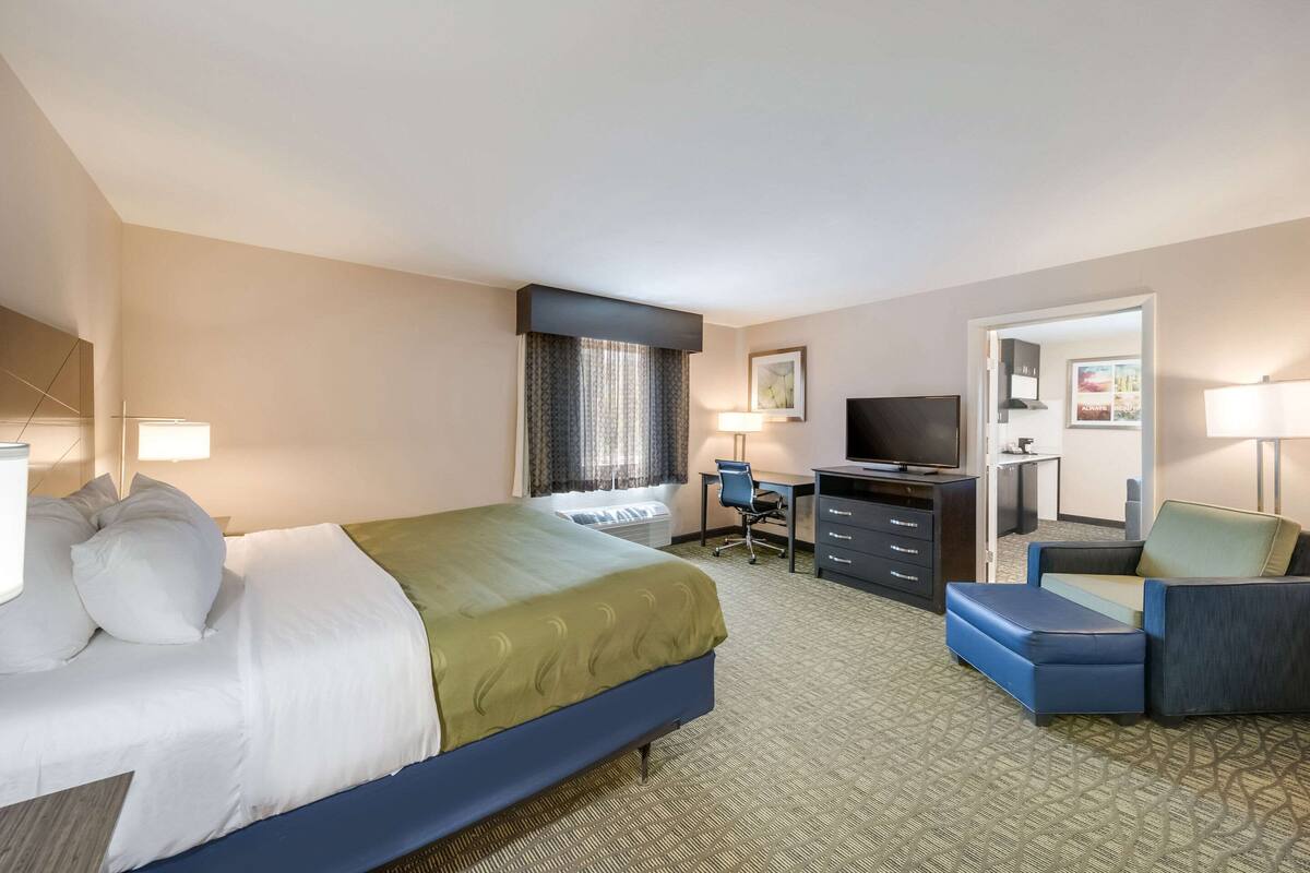 Une chambre d’hôtel avec un lit, un bureau, une télévision et une chaise.