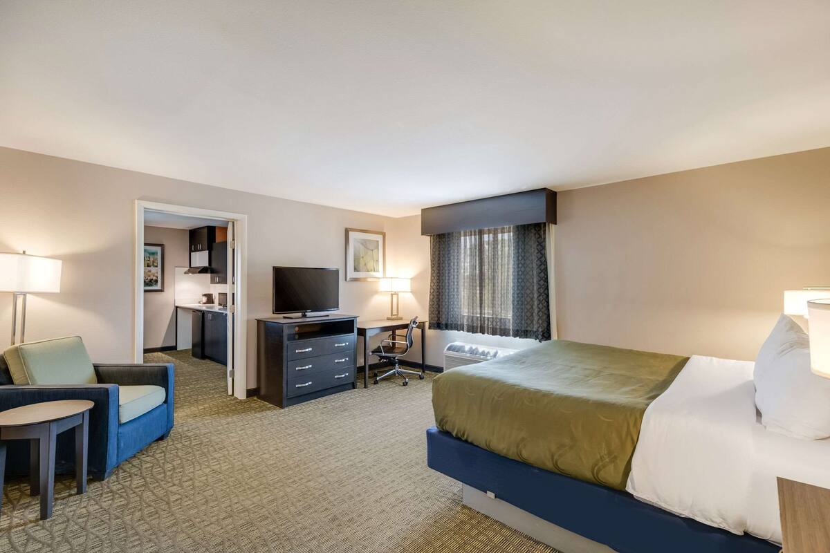 Une chambre d’hôtel équipée d’un lit, d’un bureau, d’une chaise, d’une télévision et d’une lampe.