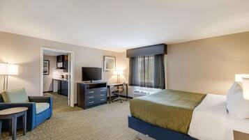 Quarto de hotel com uma cama, escrivaninha, cadeira, televisão e abajur.