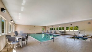 An indoor swimming pool with a tiled floor, a pool table, and a seating area with chairs. - Quality Inn & Suites Ardmore (Ardmore)