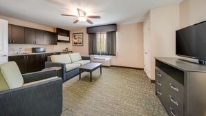A compact living space with a kitchenette, a sofa, a coffee table, a flat-screen TV, and a ceiling fan. - Quality Inn & Suites Ardmore (Ardmore)