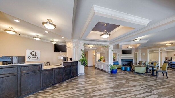 A hotel reception area with a reception desk, a sign reading "Quality by Choice Hotel", and a TV mounted on the wall. - Quality Inn & Suites Ardmore (Ardmore)