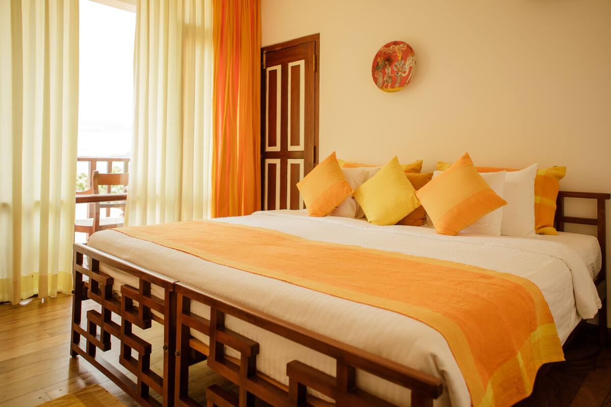 A neatly made bed with a wooden frame and a white and orange bedspread.