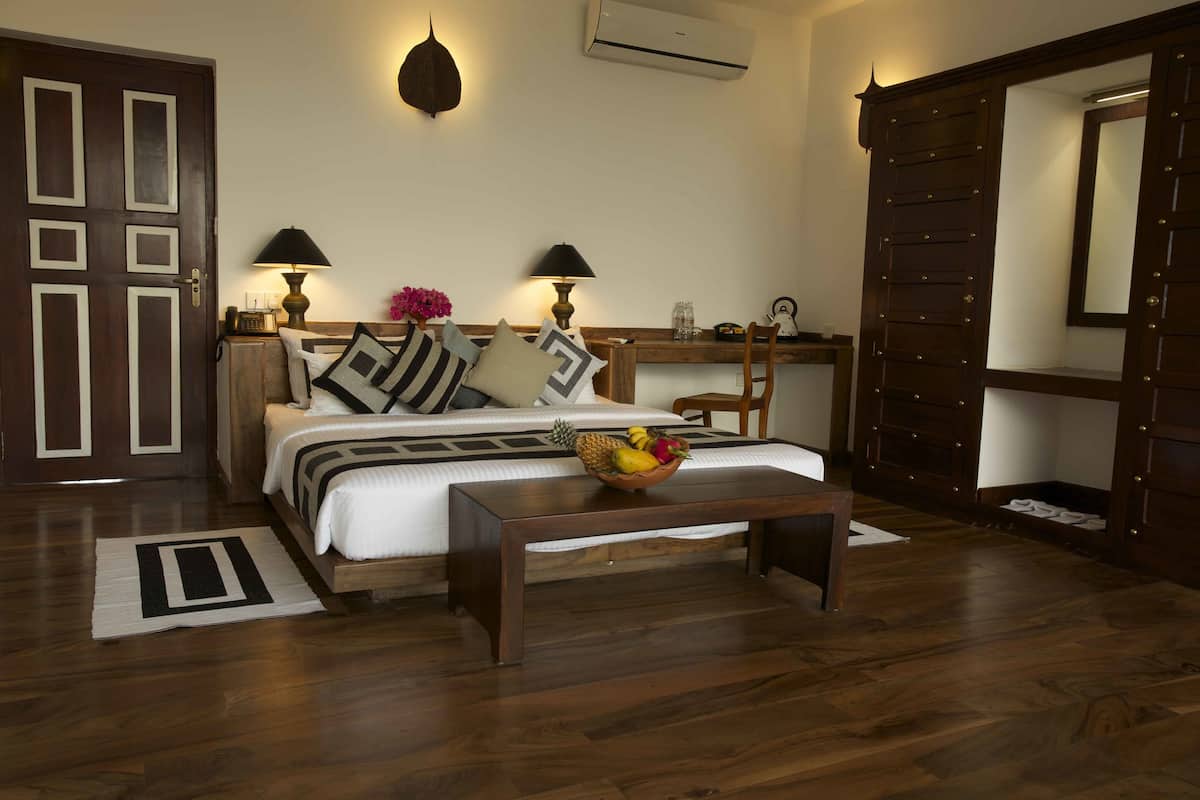 A bedroom with a bed, bedside lamps, a wooden desk, and a mirror.