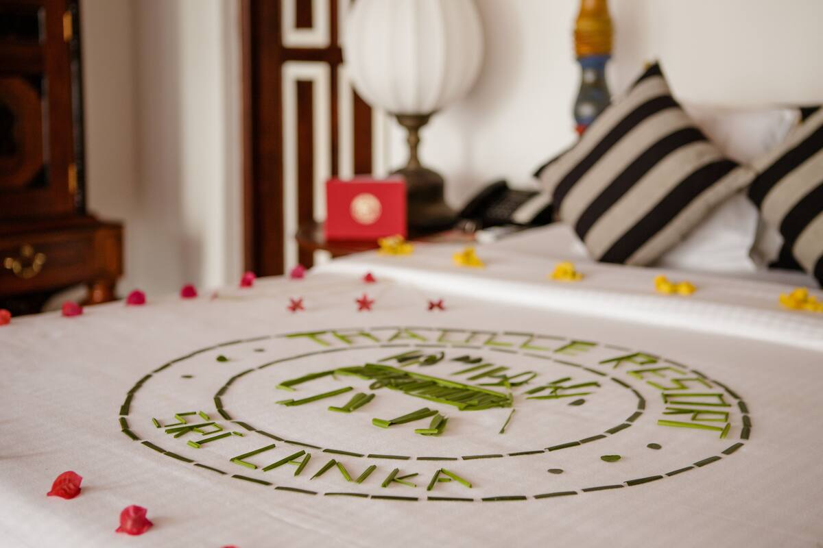 A bed with a circular design and text, surrounded by scattered rose petals.