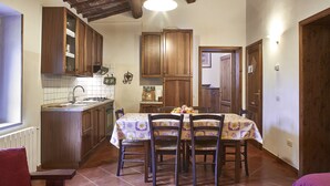 A kitchen with wooden cabinets, a dining table with chairs, and a tiled floor. - Podere Campofossato (Pistoia)