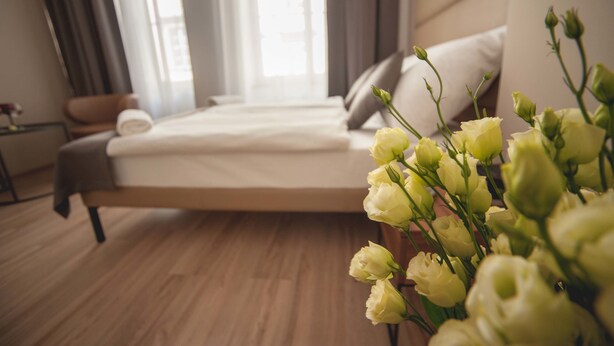 A bedroom with a bed, a nightstand, and a vase of flowers. - G12 Aparthotel (Kraków)