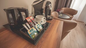 A hotel room with a coffee maker, a cup, and a tray with coffee pods. - G12 Aparthotel (Kraków)