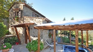 A stone building with a wooden pergola and a hot tub in the backyard. - Villa Margherita Tre (Cortona)