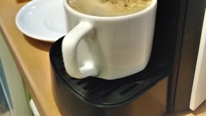 A coffee machine dispensing coffee into a white mug. - Pia Aparts (Kemer)