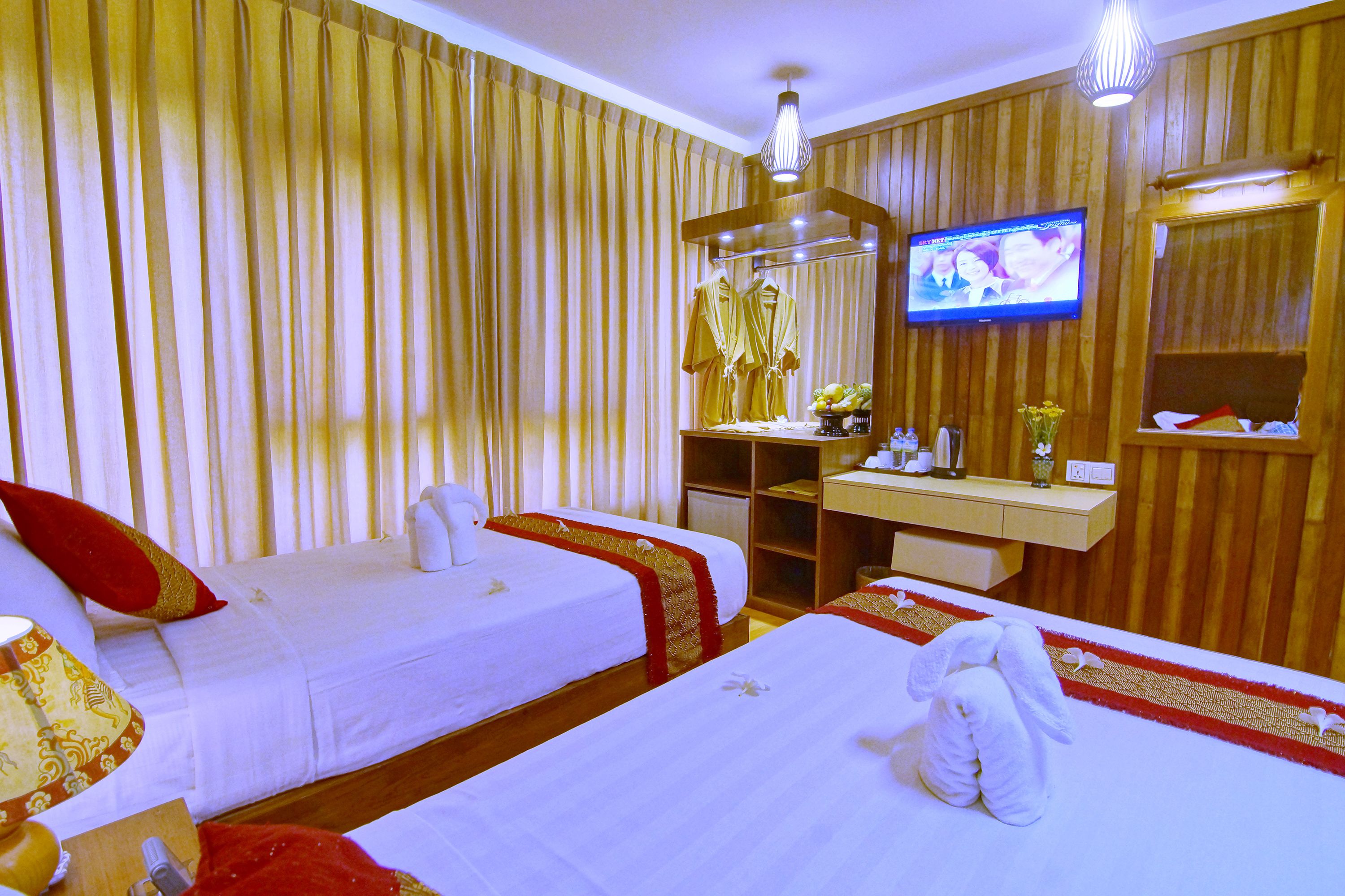 A hotel room with two beds, a TV, a desk with a mirror, and a wardrobe.
