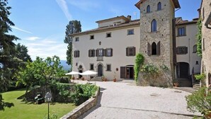 A stone building with a tower, a courtyard, and a view of the sea. - Civetta (Capolona)