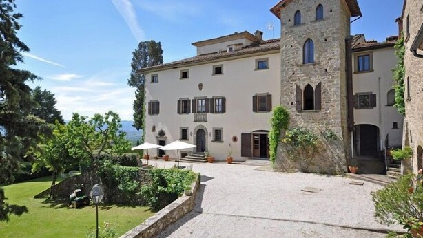 A stone building with a tower, a courtyard, and a view of the sea. - Civetta (Capolona)