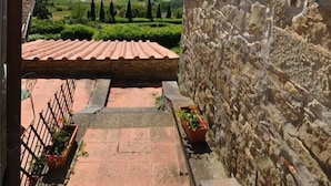 A stone wall with a tiled roof, a hanging lantern, and a view of a green landscape. - Civetta (Capolona)