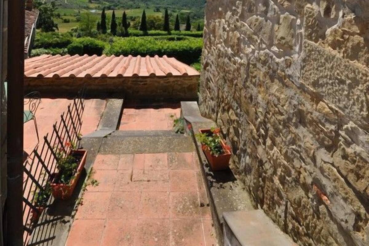 A stone wall with a tiled roof, a hanging lantern, and a view of a green landscape.