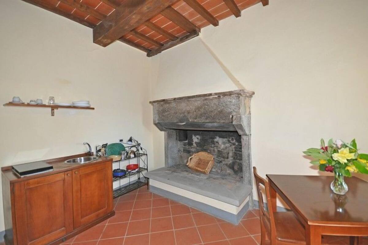 A kitchen with a stone fireplace, wooden cabinets, and a tiled floor.