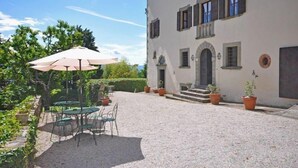 A building with a gravel courtyard, outdoor seating with tables and chairs, and potted plants. - Civetta (Capolona)